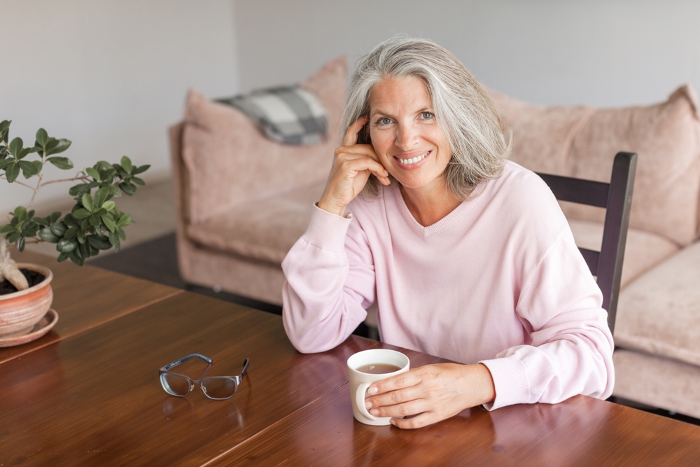 Happy mature woman at home drinking coffee
